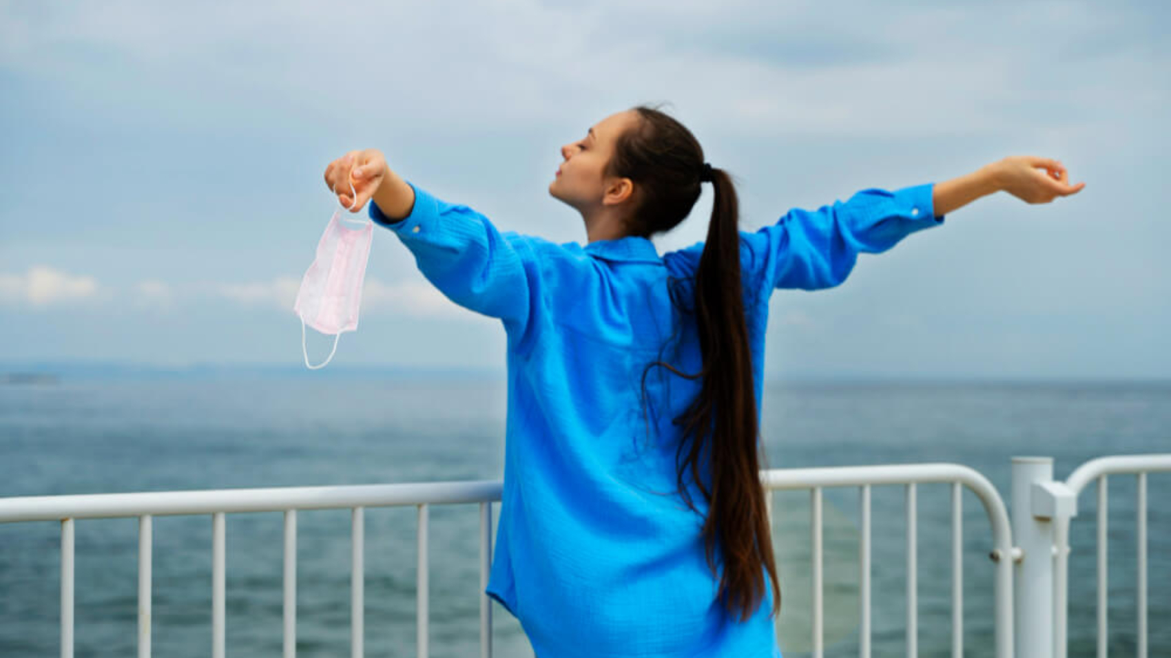 side-view-woman-holding-face-mask-seaside (1)